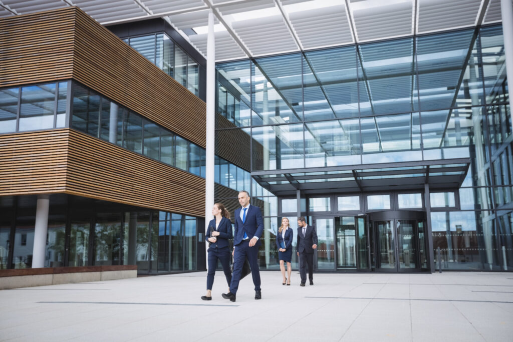 Group of business people walking outside the entrance of an office building